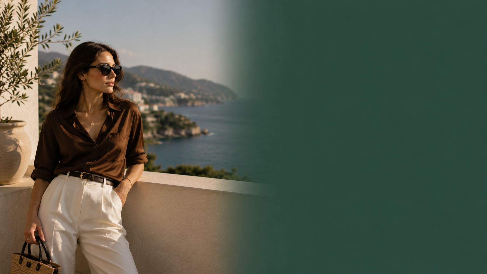 A woman wearing a brown button-up shirt, white trousers, and sunglasses stands on a balcony overlooking a coastal sea and mountains, with a large dark green graphic overlay on the right side of the frame.